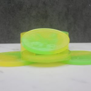 Four round, circle-shaped resin coasters stacked in and around a holder that has 1/3 of the perimeter cut out of it. They are swirled in bright yellow and bright green, called the "Lemon Lime" colorway