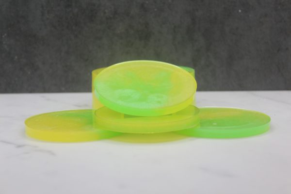 Four round, circle-shaped resin coasters stacked in and around a holder that has 1/3 of the perimeter cut out of it. They are swirled in bright yellow and bright green, called the "Lemon Lime" colorway
