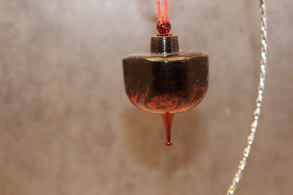 Burgundy bowl shaped ornament with firey design worked into the bottom of the resin. Metallic red hood on top and matching decorative post on the bottom. There is a red sparkly mesh ribbon loop tied to the loop of the ornament that it is hanging from