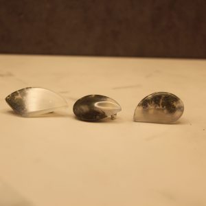 Three shiny polished agate stone pins, 2 teardrop shaped and one rounded, angular shape. They each vary in color, about half grey-brown and half opaque white with moderate chatoyancy. They vary in size but generally measure approximately 0.5 in by 1 in
