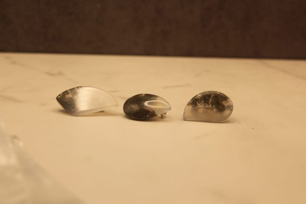 Three shiny polished agate stone pins, 2 teardrop shaped and one rounded, angular shape. They each vary in color, about half grey-brown and half opaque white with moderate chatoyancy. They vary in size but generally measure approximately 0.5 in by 1 in