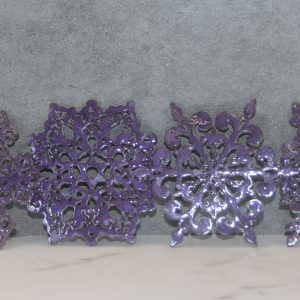 4 sparkly purple snowflake shaped coasters, each a different shape, lined up next to each other, leaning on a gray background