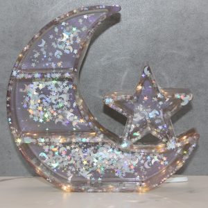 crescent moon shaped shelf with 3 shelves and a star-shaped shelf attached made of resin with star and moon shaped glitter inside and embedded battery operated LED lights