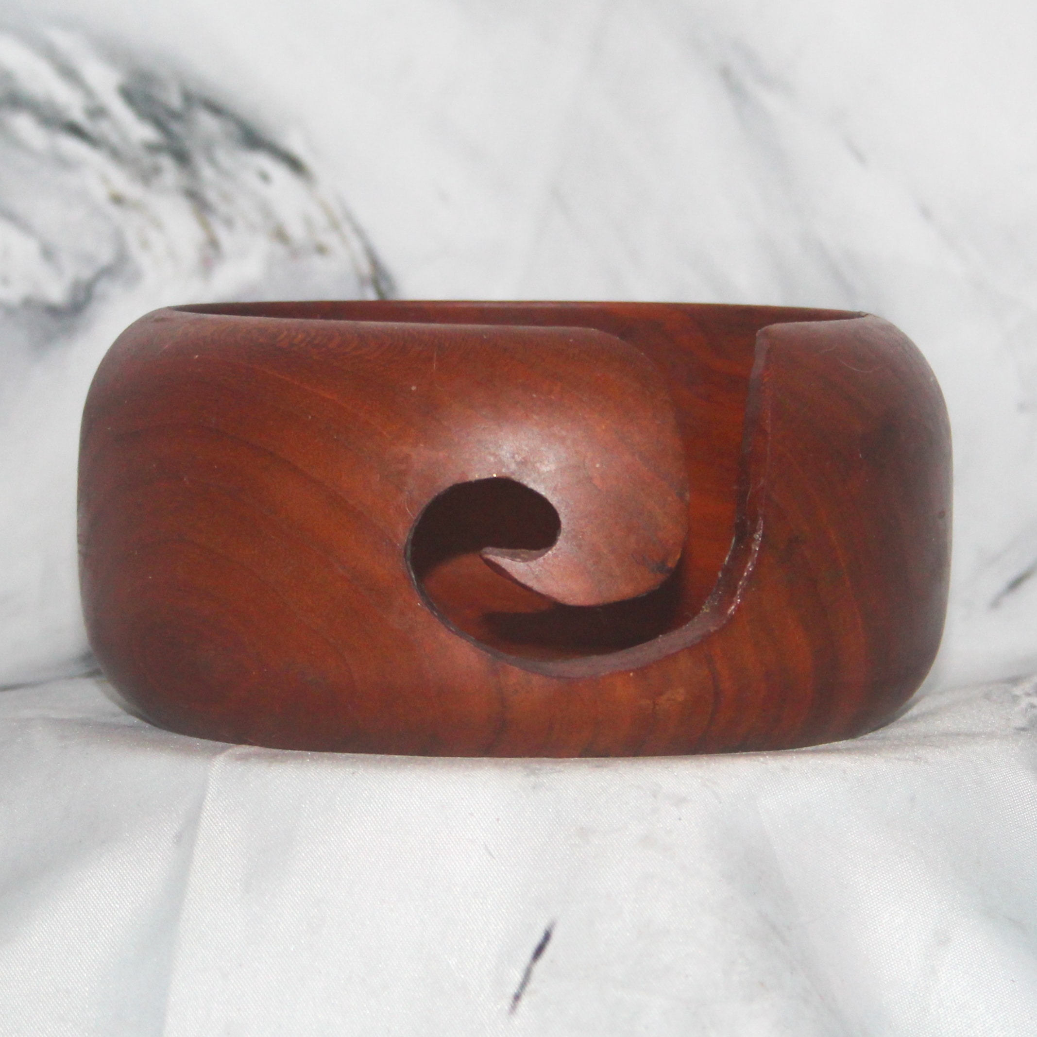 Front view of a hand-turned cherry and walnut yarn bowl showing yarn guide slot and rich wood tones, cherry walnut hand-turned yarn bowl by Sarkanys Rising