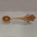 An image of a wooden spoon against a marble backdrop. The handle is an art deco shape.