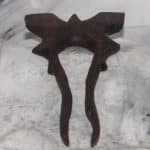 A hand-carved walnut bat bun pin with angular geometric bat silhouette, handcarved wood bun decoration by Sarkanys Rising