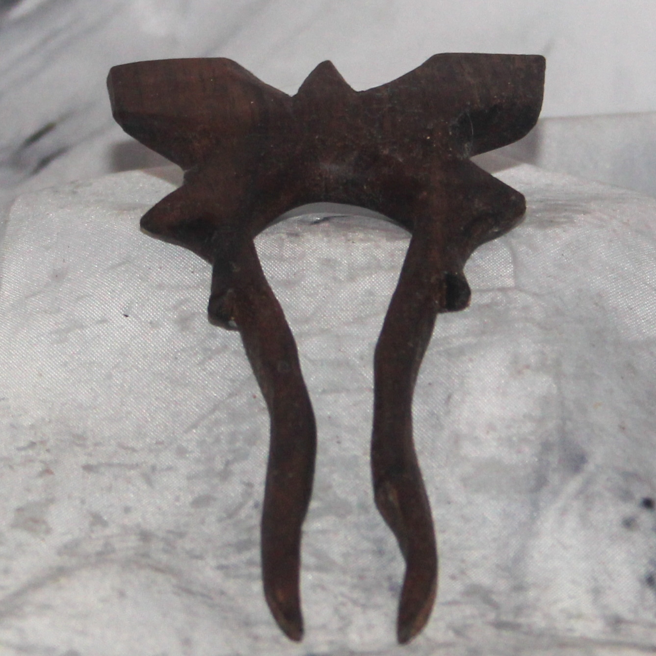 A hand-carved walnut bat bun pin with angular geometric bat silhouette, handcarved wood bun decoration by Sarkanys Rising